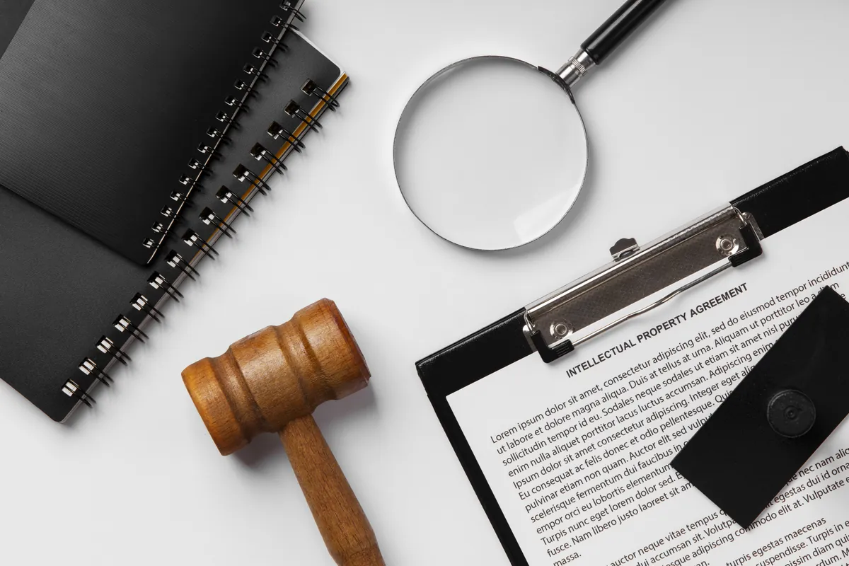 Martelo de juiz, lupa e um contrato de propriedade intelectual sobre uma mesa